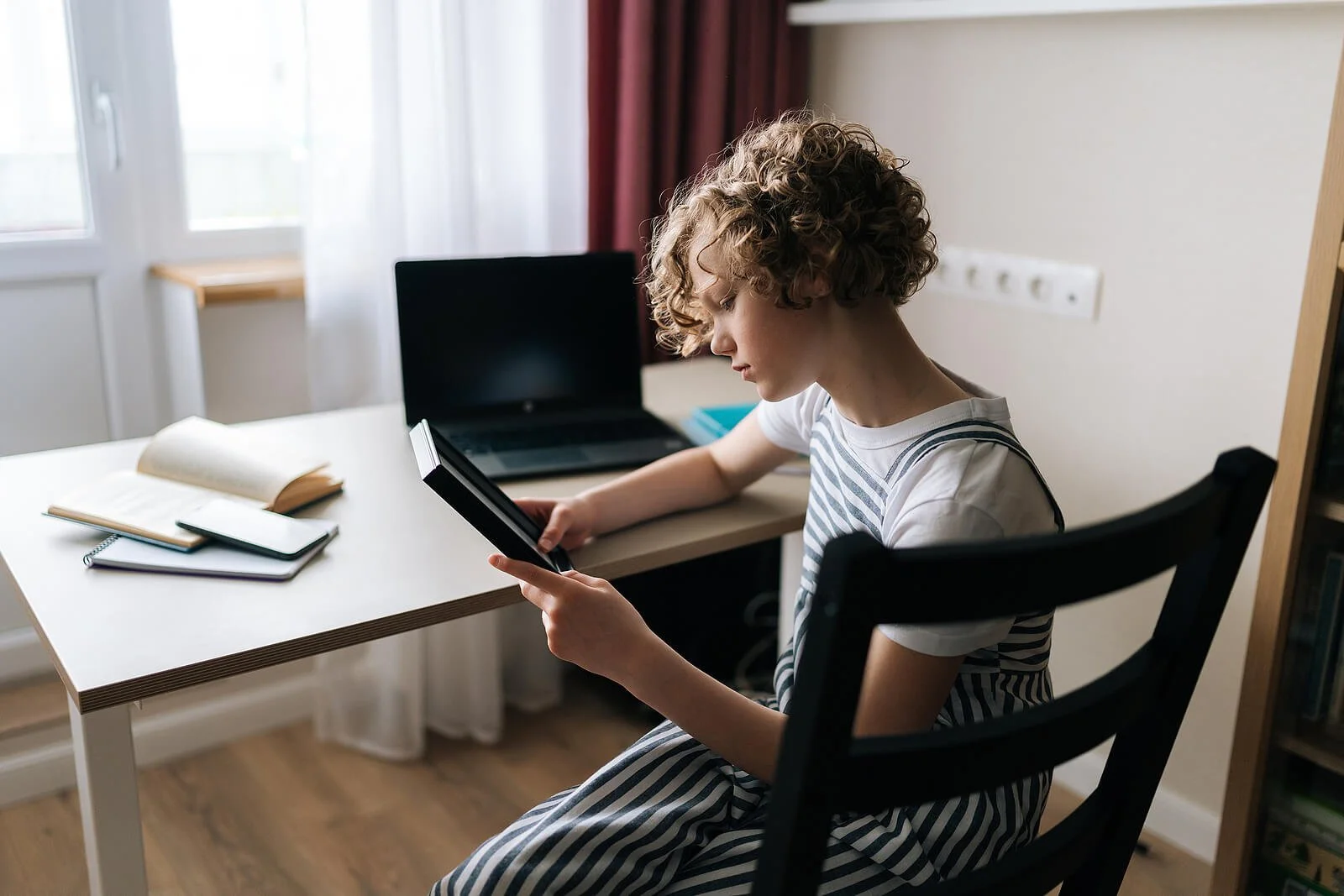 Child sitting at a desk with a tablet, representing helping children cope with divorce and family changes