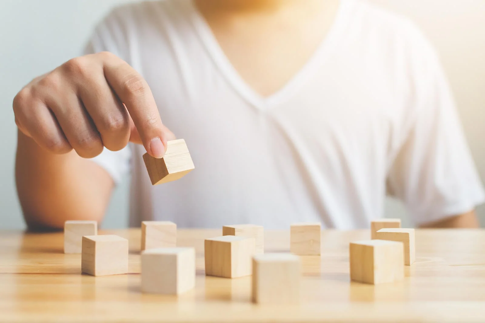 Person placing wooden blocks on a table, representing psychological testing, problem-solving, and diagnostic clarity