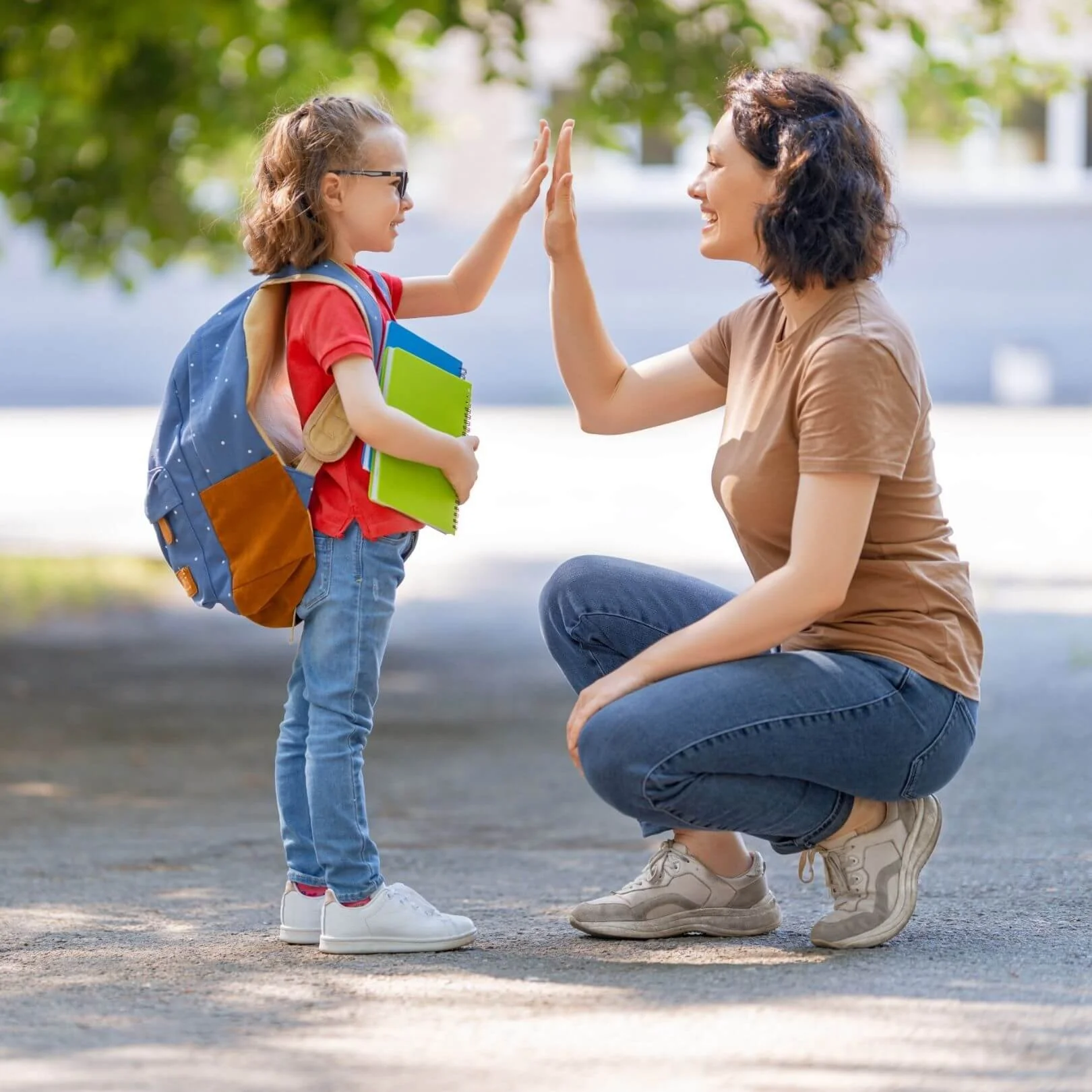 Parent and child sharing a high five outdoors, representing parenting a child with ADHD and the positive support, encouragement, and growth fostered through behavior therapy