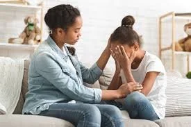 Signs of grief in a child shown by caregiver comforting upset child during emotional moment