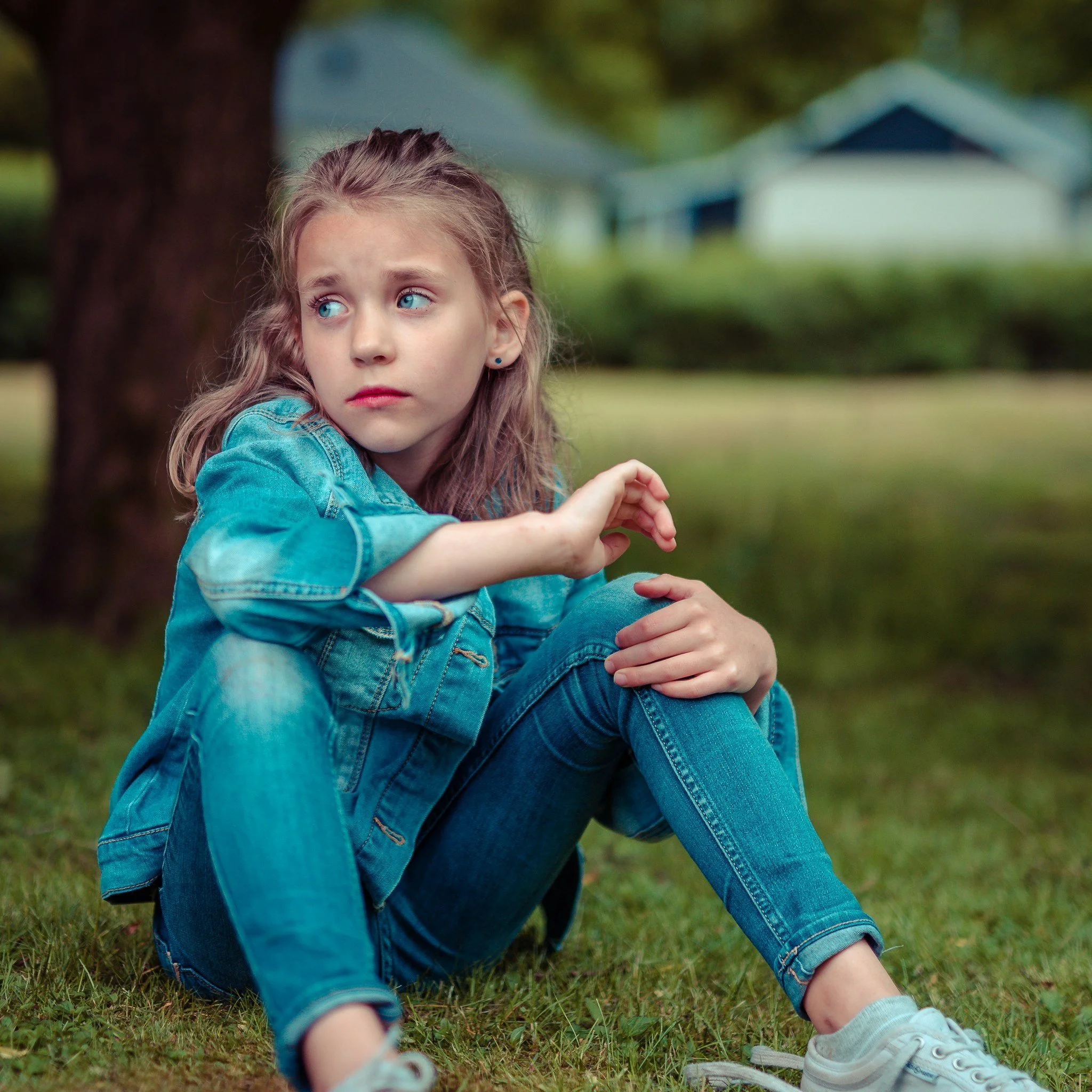 Grief in children shown by young girl sitting alone outdoors appearing sad and withdrawn