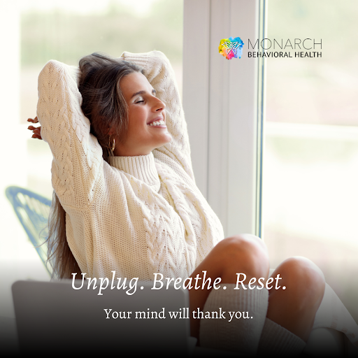 Person sitting by a window with eyes closed and arms relaxed behind their head, illustrating unplug to reset through rest, breathing, and mental renewal.