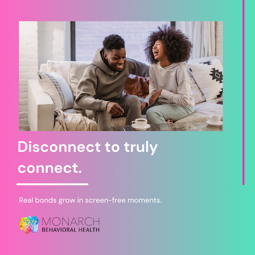 Couple sitting together on a couch laughing with phones put away, promoting unplug to reconnect and build real screen-free connections.