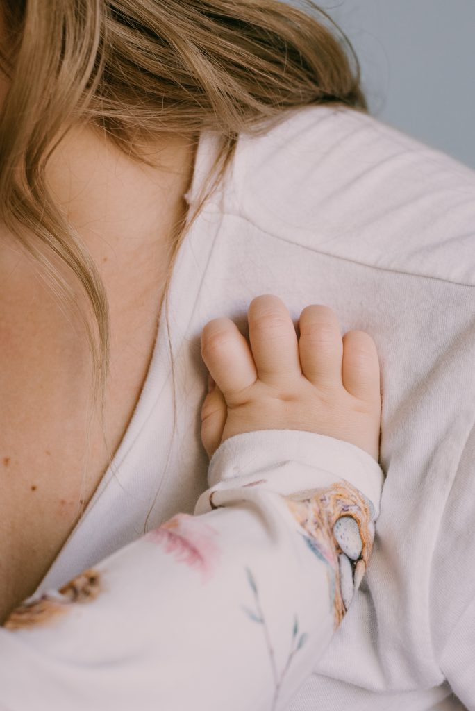 Close-up of a baby’s hand holding onto an adult’s shirt.