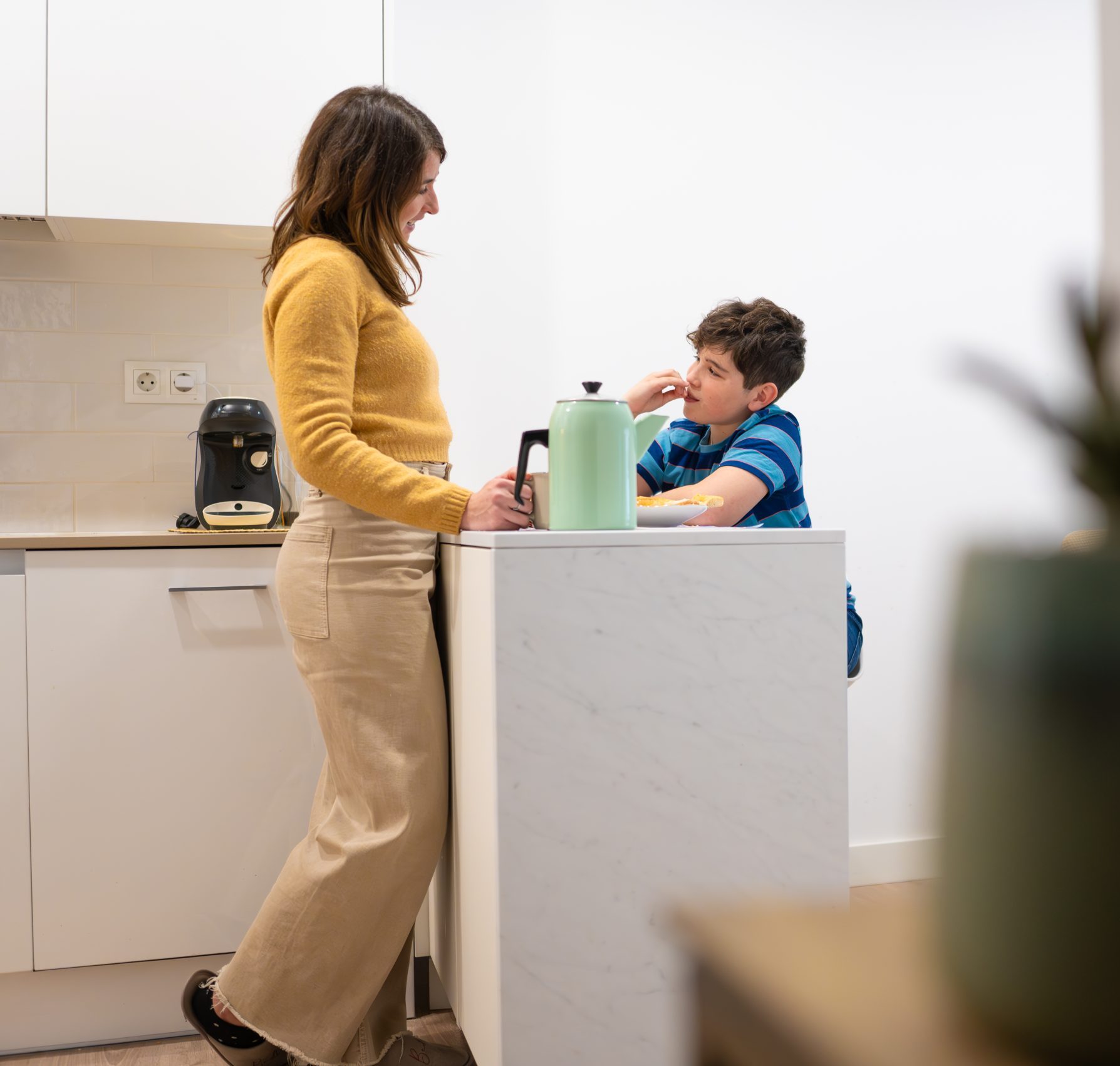Parent talking with a child while standing by the kitchen counter.