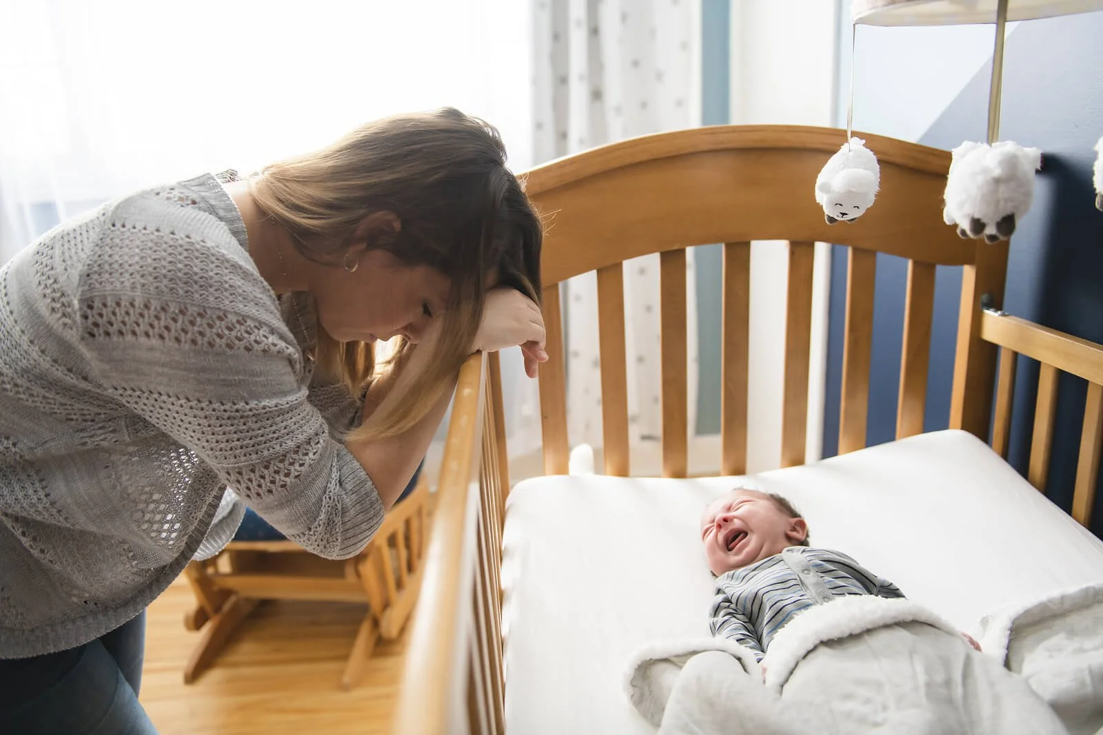  A mother hangs her head over the crib of her crying newborn. Postpartum therapy in San Antonio, TX can offer support during this time of transition. A postpartum depression therapist in San Antonio, TX can offer support today! 78258 