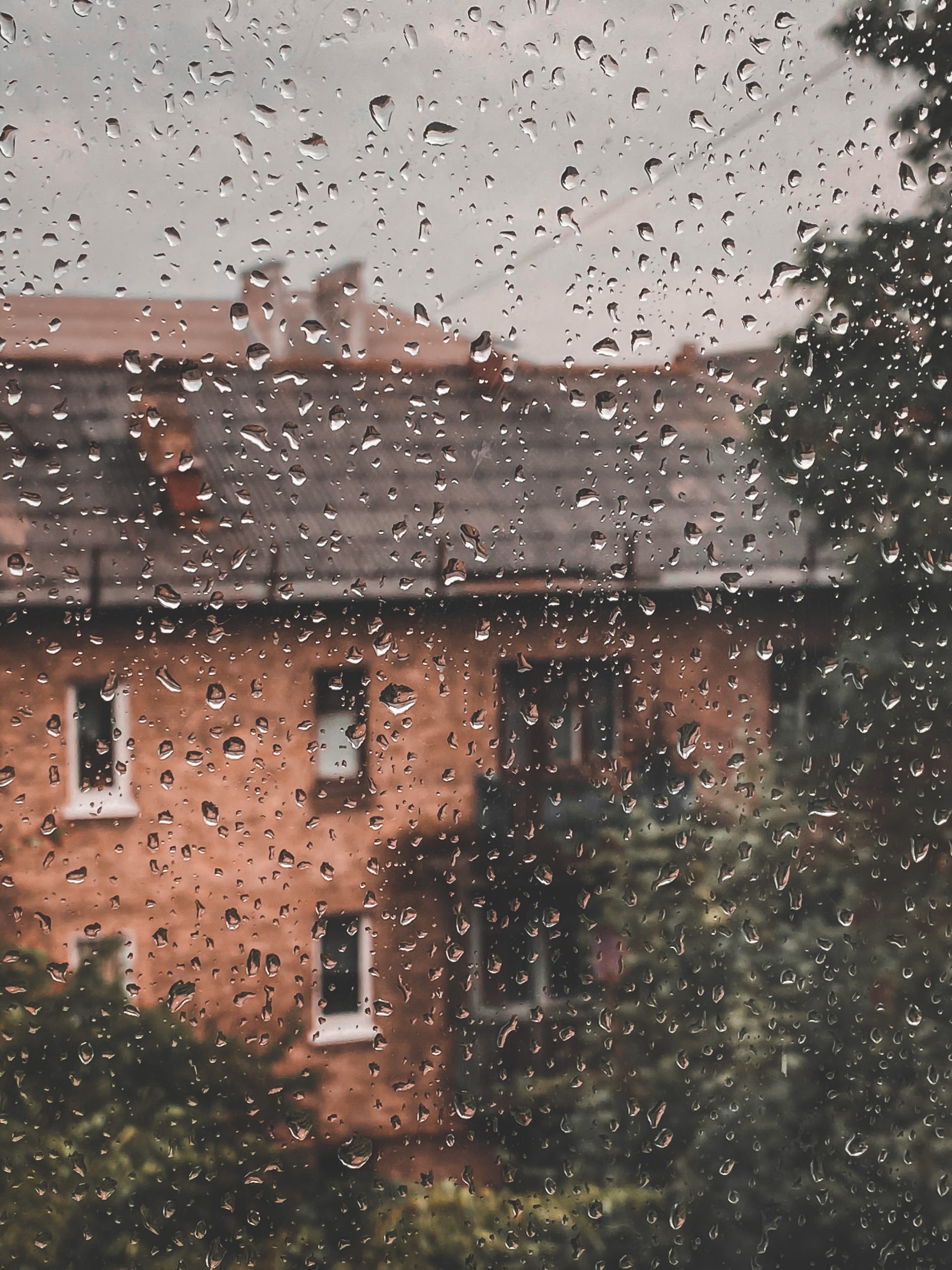 Brick building seen through a rain-covered window with water droplets.