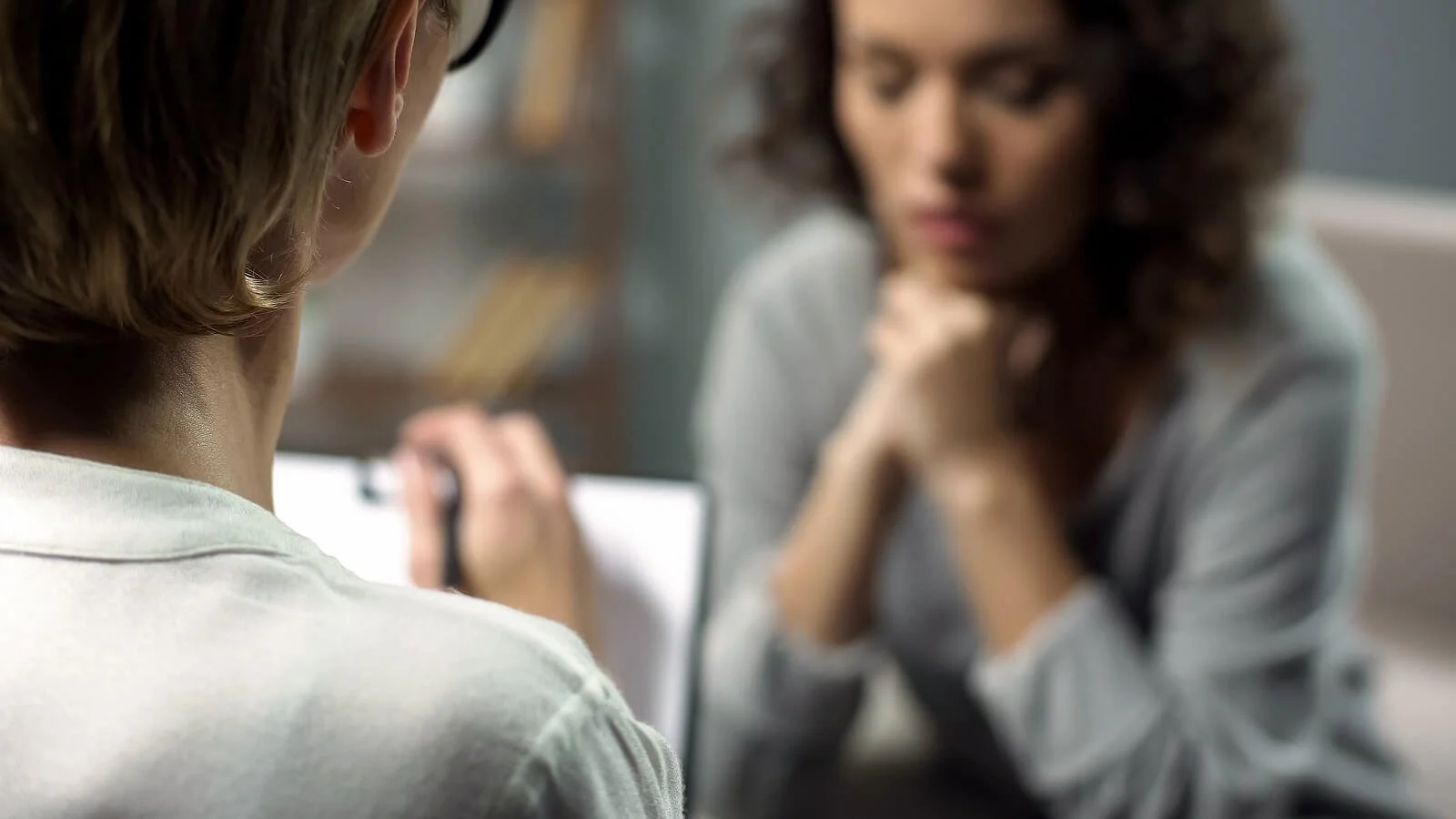  A close-up of a therapist writing on a clipboard as a client sits across from them. This could represent a postpartum therapist in San Antonio, TX meeting for postpartum anxiety treatment in San Antonio, TX or postpartum depression treatment today! 78258 