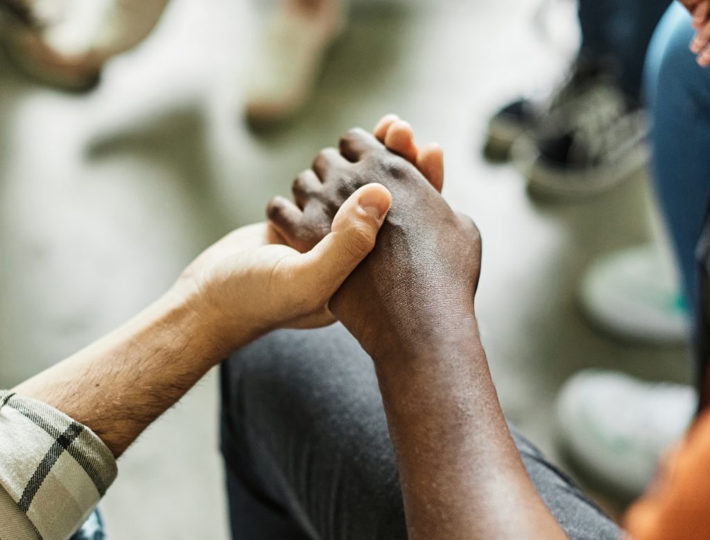 Two people holding hands in a gesture of comfort and support.