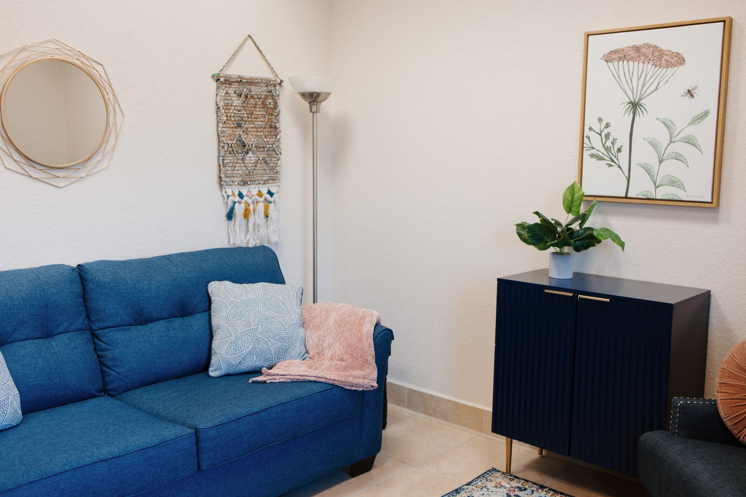 Bright therapy office with blue sofa, pillows, and wall art.