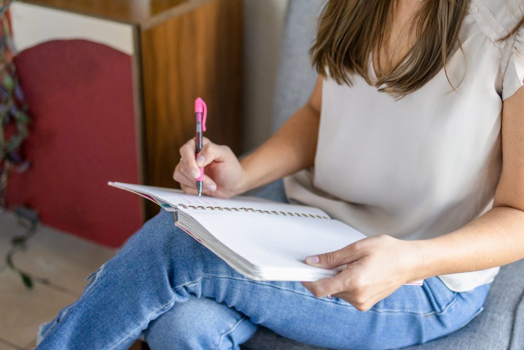 Woman sitting and journaling with a notebook and pen.