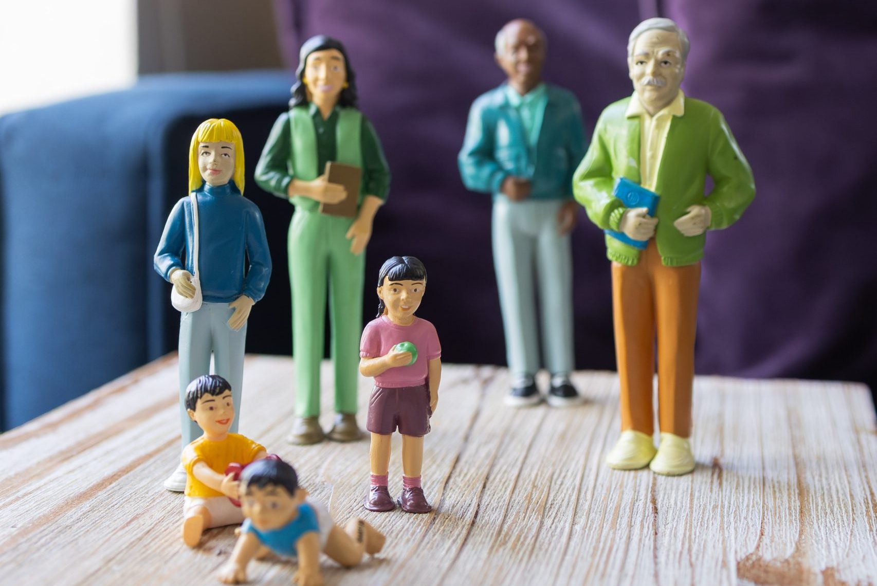 Toy family figurines standing together on a wooden surface.