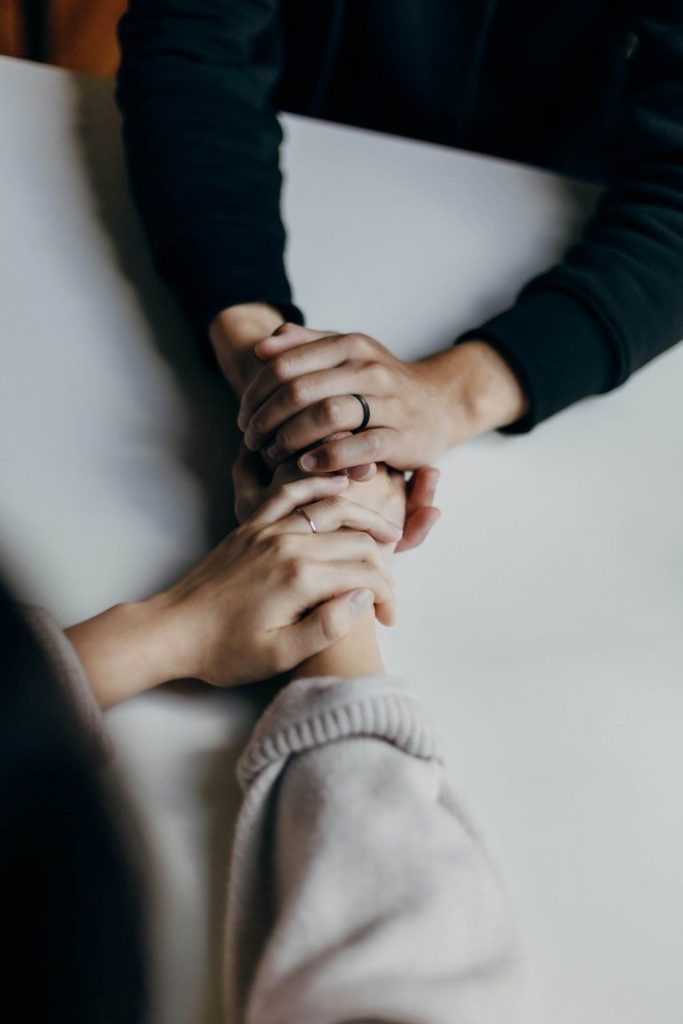 Two people holding hands in a comforting, supportive gesture.