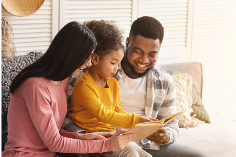 Father, mother, and daughter sitting together reading from a tablet or book.