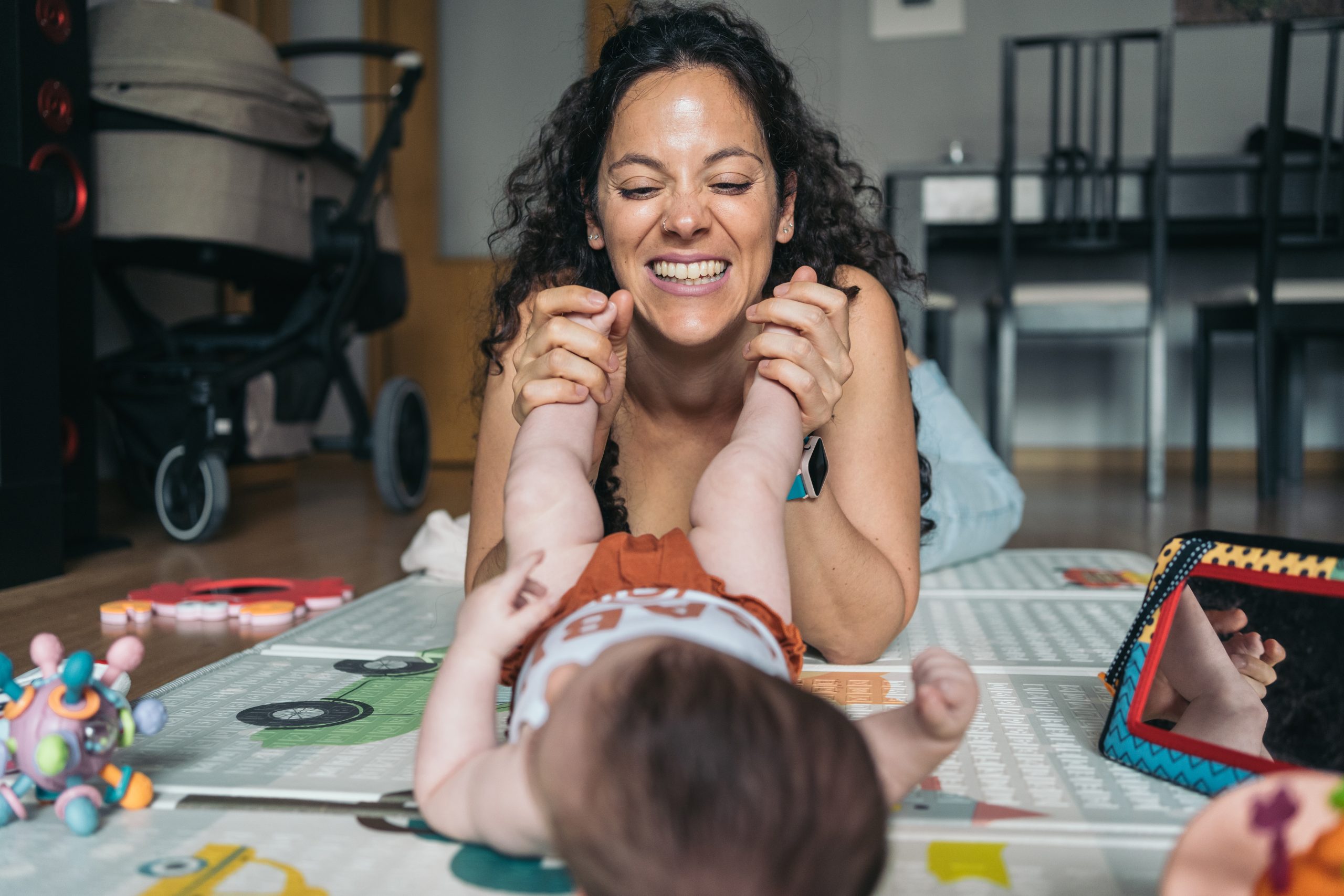 Parent smiling and playing a game with a young child at a table.