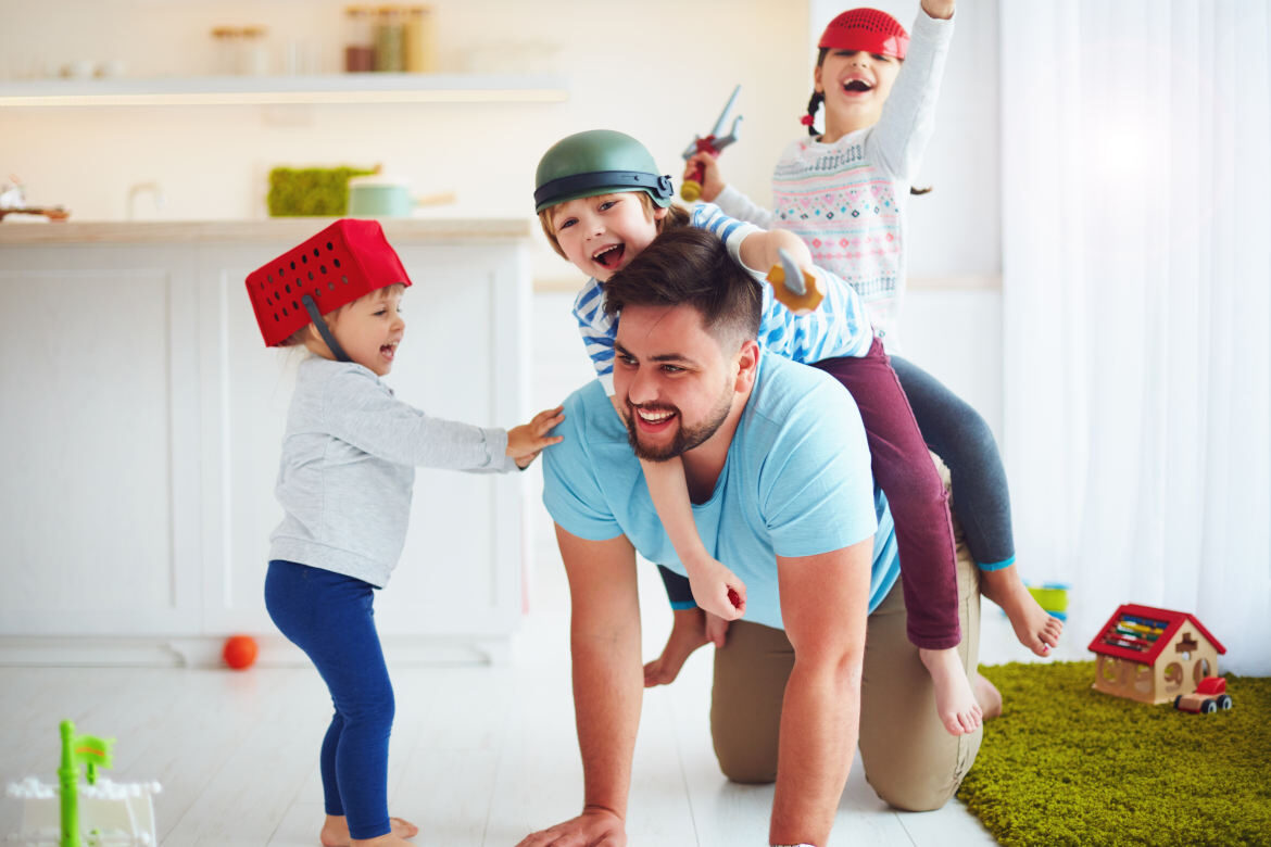 Parents playing and laughing with their young children on the floor.