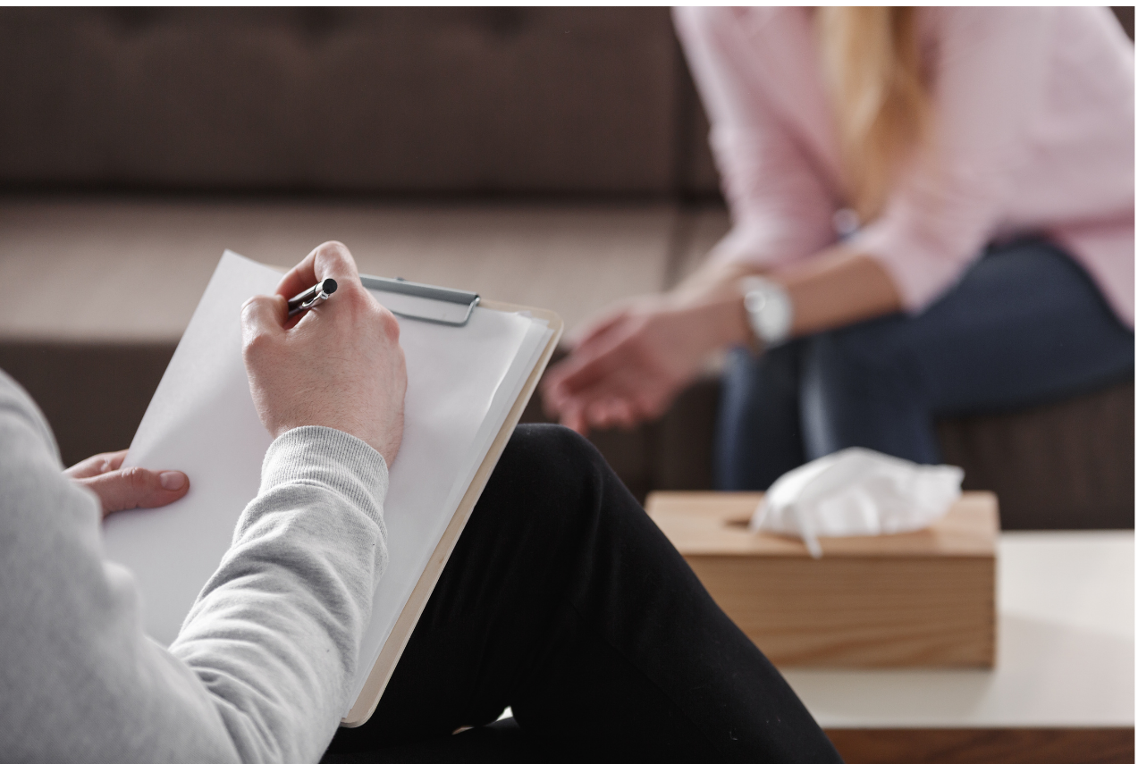 Person reclining with knees bent while journaling in a notebook.