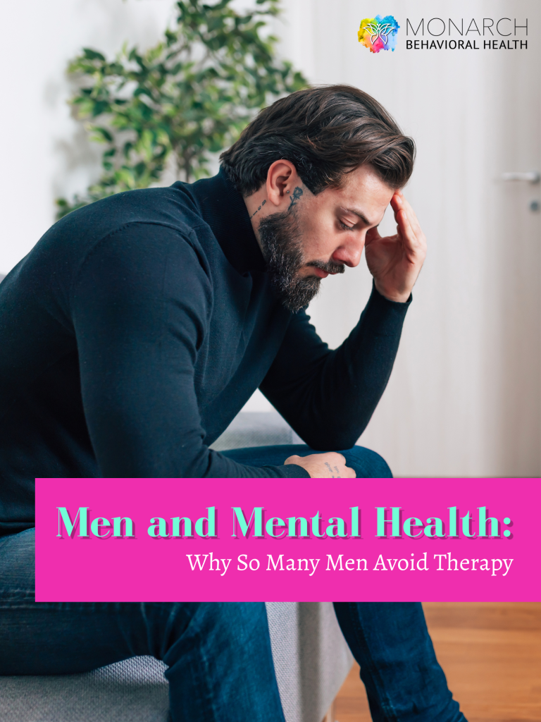 A bearded man with neck tattoos in a black turtleneck sits hunched over with his hand pressed to his temple, looking downward in distress illustrating why so many men avoid seeking men's therapy in San Antonio, featured by Monarch Behavioral Health